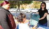 San Mateo County staff distributing a backpack to a family.